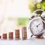 Stack of coins and alarm clock symbolizing financial growth and time management for Allore's Plumbing Services.