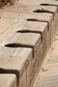 Ancient stone toilet seats illustrating early sanitation practices, relevant to the history of toilets discussed in the context of plumbing advancements.