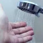 Showerhead dispensing water over a hand, highlighting personal care and cleanliness in home improvement.