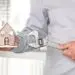 Person measuring a model house, demonstrating plumbing planning for homeowners. Allore's Plumbing Services LLC.