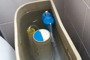 Toilet tank with water level visible, featuring float mechanism components for adjusting water pressure and flush functionality.