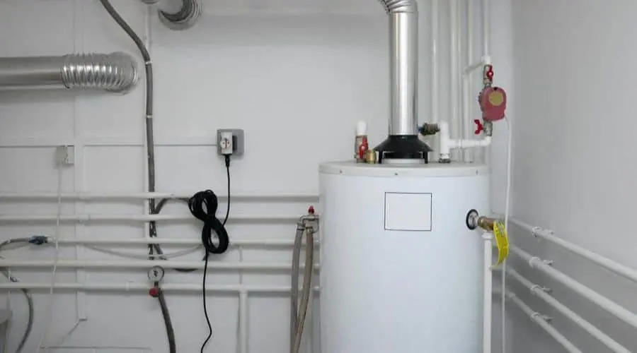 Water heater with vertical silver pipes, electrical connections, and a black cord in a mechanical utility room.