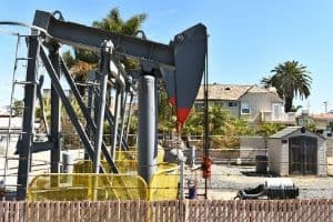 Well pump system with a pump jack, surrounding residential area, showcasing components essential for water access in homes without city supply.