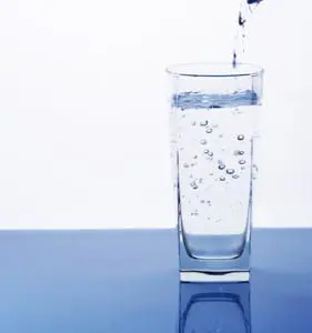 Stuart Plumber Glass of water being filled, showcasing bubbles and clarity, emphasizing benefits of water softening systems for cleaner and smoother water.