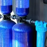 Blue water filtration tanks with piping system&mdash;expert plumbing services by Allore's Plumbing Services LLC.