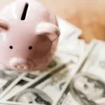 Pink piggy bank with scattered dollar bills, symbolizing savings for Allore's Plumbing Services LLC.