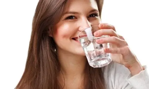 Smiling woman holding a glass of clean water, illustrating the benefits of water filtration and treatment for improved water quality.