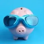 Piggy bank with blue goggles on light blue background, representing Allore's plumbing services' fun approach to savings.