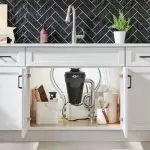 Garbage disposal unit in modern kitchen with cleaning supplies and storage, from Allore's Plumbing Services LLC.