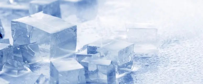 Ice cubes on a wet surface, illustrating the refreshing quality of softened water for drinking and household use.