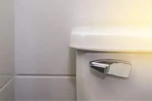 Toilet flush handle on a white toilet tank, illustrating a common plumbing issue related to faulty flush mechanisms.