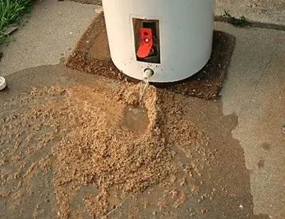 Sediment and water draining from a water heater, indicating buildup and maintenance needs for optimal plumbing function.