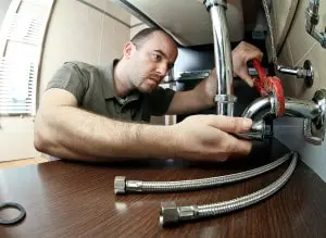 Stuart plumber Man using a wrench to repair plumbing under a sink, demonstrating professional plumbing techniques for effective home repairs.