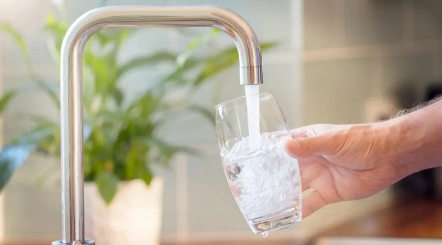 Glass filled with water from a modern faucet, highlighting plumbing services by Allore's Plumbing Services LLC.
