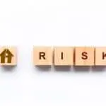 Wooden letter cubes spelling "RISK," one with a house icon, related to plumbing for holiday property maintenance.