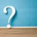 3D question mark symbol against a light blue wall and wooden floor, illustrating inquiry in plumbing maintenance topics.