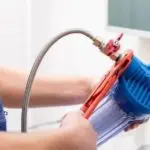 Person using a water filtration device, showcasing plumbing maintenance for homeowners by Allore's Plumbing Services LLC.