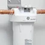 Water filter system with copper pipes and white casing, showcasing Allore's Plumbing Services logo and specifications.