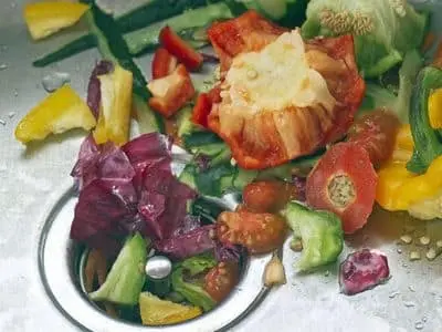 Food scraps and vegetable peels in a kitchen sink drain, illustrating common waste that can lead to clogs and plumbing issues.
