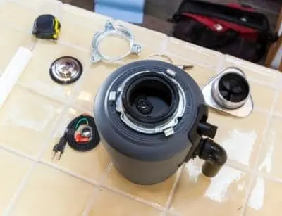 Garbage disposal unit with visible components on a kitchen countertop, emphasizing installation for effective plumbing maintenance and preventing clogs from food waste.