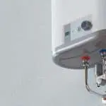 Modern water heater featuring a control panel with digital display and colored inlet/outlet pipes.
