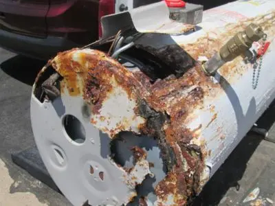 Corroded and damaged storage water heater tank showing severe rust and deterioration, indicating the need for replacement to prevent leaks and water damage.