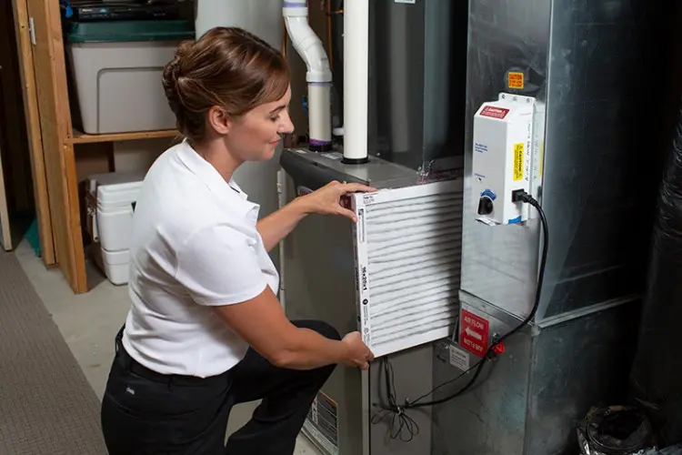 Woman replacing a furnace filter in a residential setting, demonstrating HVAC maintenance for Superior Plumbing, Heating & Air-Conditioning services.