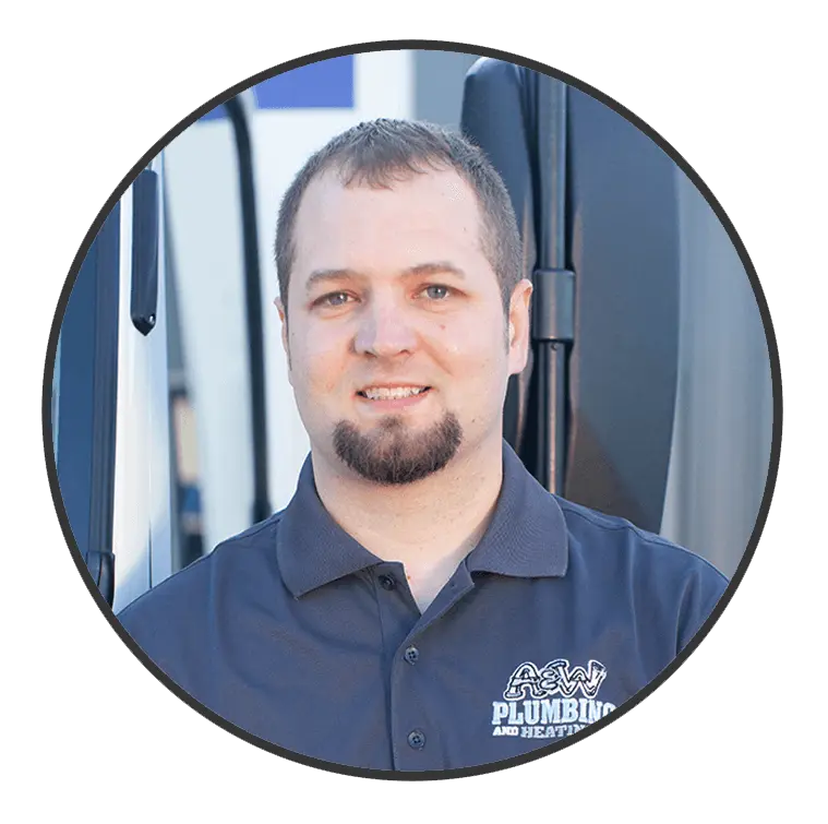 A&W Plumbing and Heating team member smiling in a branded polo shirt, with service vehicles in the background, representing the company's commitment to quality plumbing and heating services.