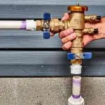 Water control valve system from A & W Plumbing, featuring blue and purple handles on a gray wooden background.