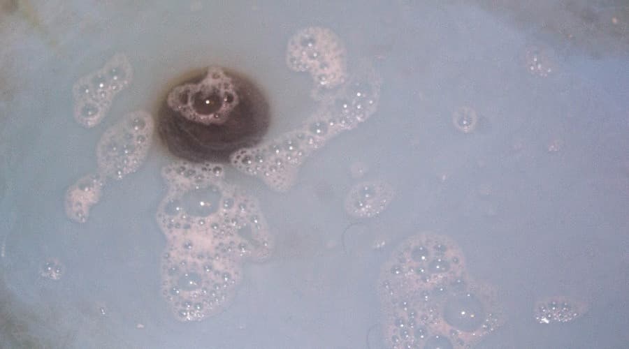 Bubbling water around a drain, indicating potential sewer line issues, relevant to plumbing maintenance and repair.