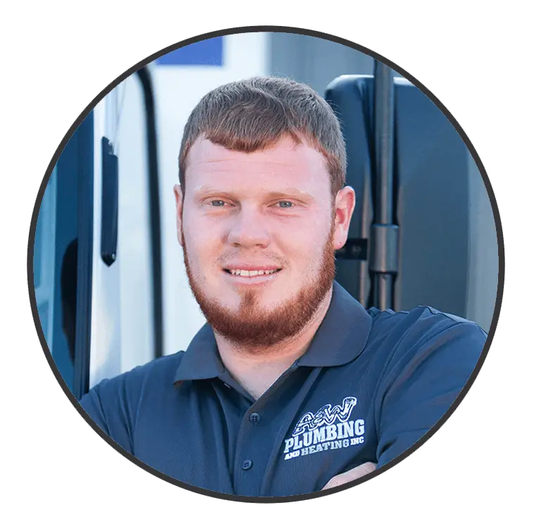 Team member of A & W Plumbing and Heating, Inc., smiling in a branded polo shirt, standing beside a service vehicle, emphasizing professionalism and approachability.