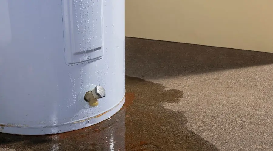 Water heater with visible water leakage on the floor, highlighting potential repair needs for plumbing services in Murphysboro, IL.