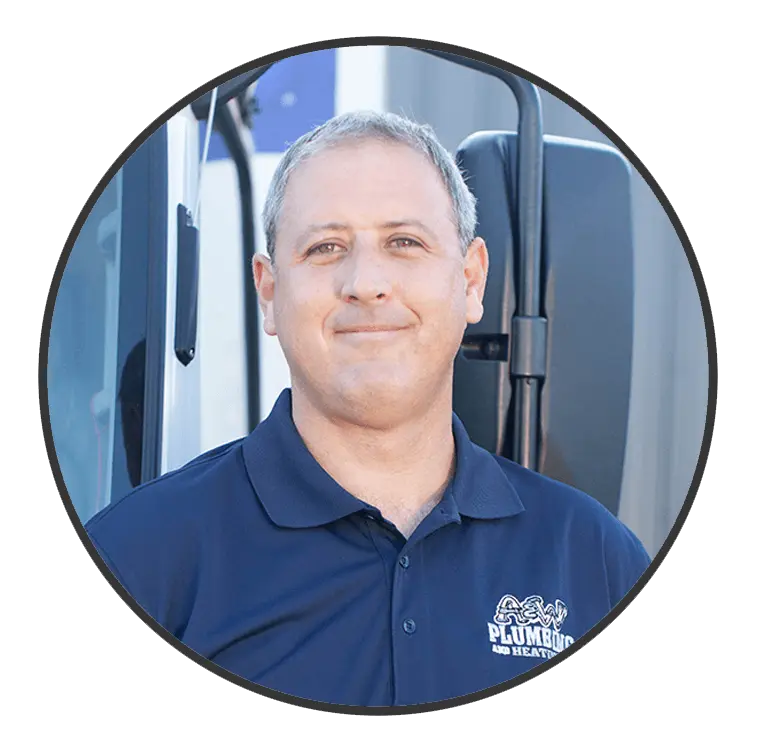 Plumber smiling in uniform with A & W Plumbing and Heating logo, standing next to service vehicle, representing the dedicated team at A & W Plumbing and Heating, Inc.