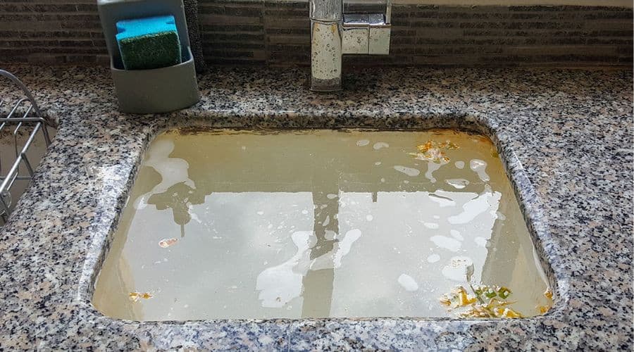 Dirty sink with cloudy water and debris, showcasing plumbing issues at A & W Plumbing and Heating.