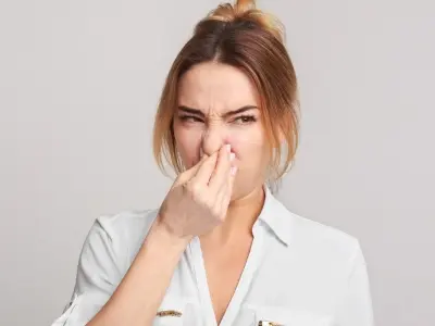 Woman holding her nose in disgust, indicating foul smells associated with clogged sewer lines, reflecting signs of plumbing issues.