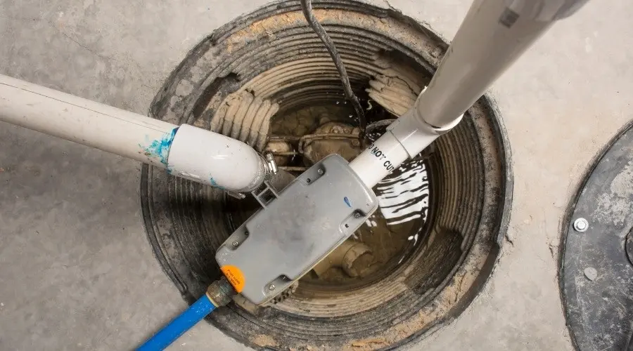Sump pump system installed in a basement, featuring a pump, discharge pipes, and water, illustrating plumbing solutions for flood protection.