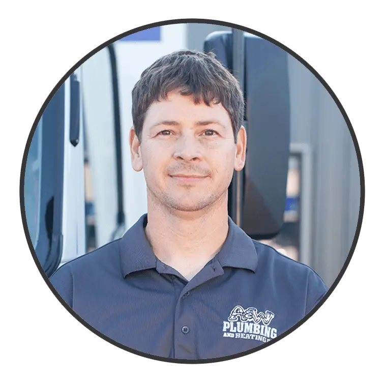 Plumber from A & W Plumbing and Heating, Inc. wearing a branded shirt, standing in front of a service vehicle, showcasing professionalism and expertise.