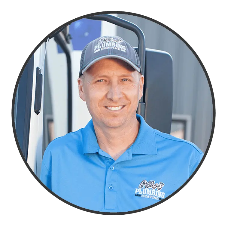 Smiling plumber in blue A & W Plumbing and Heating uniform, showcasing professionalism and approachability, with service vehicle in background.
