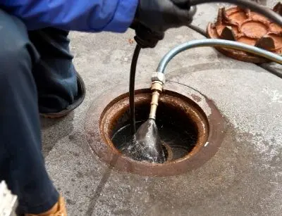 Professional using hydrojetting equipment to clear a clogged outdoor drain, demonstrating effective plumbing maintenance techniques.