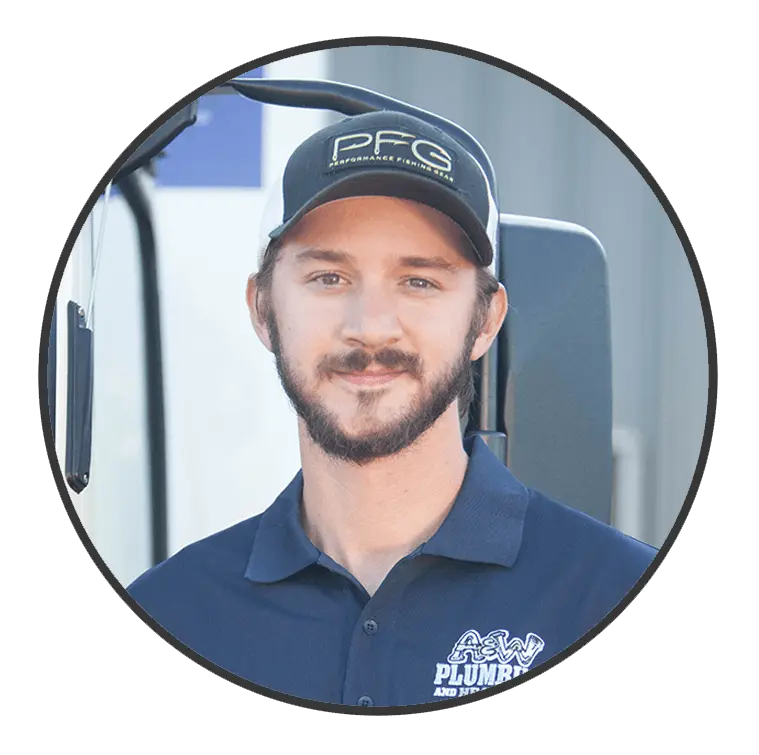 Plumber from A & W Plumbing and Heating, Inc. wearing a branded shirt and cap, smiling in front of a service vehicle.