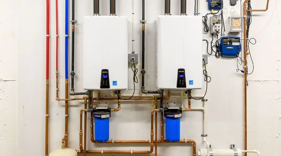 Tankless water heaters with digital displays and copper piping at A & W Plumbing, showcasing modern plumbing solutions.
