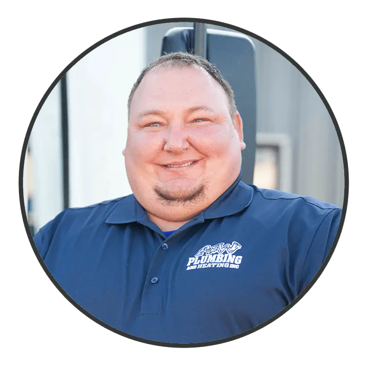 Smiling male technician wearing a navy blue A & W Plumbing and Heating, Inc. polo shirt, standing outdoors, showcasing the company's commitment to quality service.
