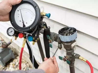 Backflow testing equipment being used on a backflow prevention device, illustrating the process of ensuring safe municipal water services and compliance with plumbing regulations.
