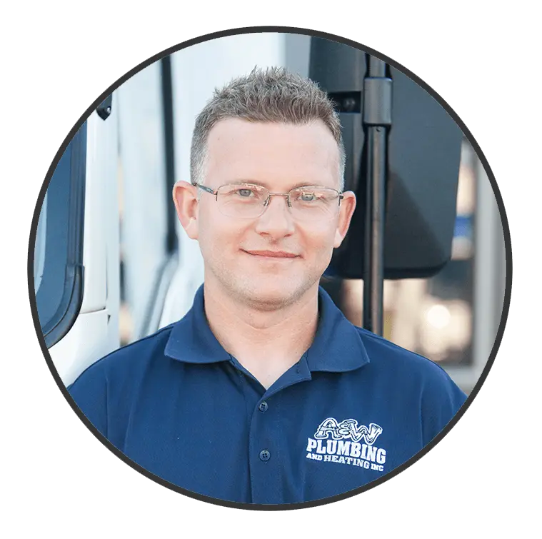 Plumber from A & W Plumbing and Heating, Inc. wearing a blue uniform with company logo, standing in front of a service vehicle.