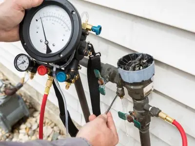 Backflow testing equipment being used to assess a backflow prevention device, highlighting the importance of plumbing safety and contamination prevention.