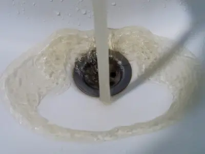 Water flowing into a sink drain, illustrating the concept of backflow in plumbing systems related to water contamination risks.