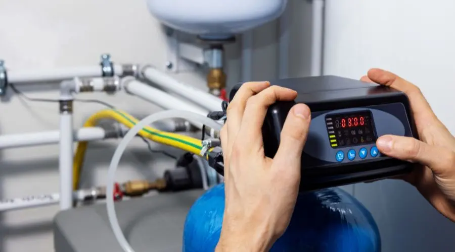 Hands adjusting digital control panel on water filtration system, showcasing plumbing technology relevant to B & D Plumbing, Heating & A/C services.