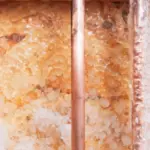 Copper pipes with crystalline formations showcasing texture and warm colors, emphasizing plumbing for winter protection.