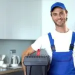 Male technician in blue cap and overalls ready to assist with plumbing services.