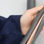 Hand holding a metal cylinder with foam insulation, related to B & D Plumbing, Heating & A/C services.